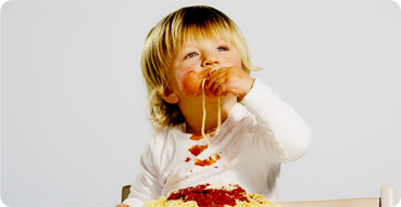 Baby eating spaghetti on a white shirt